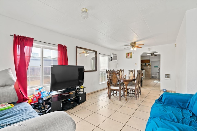 living area featuring a wall mounted AC, light tile patterned flooring, and a ceiling fan