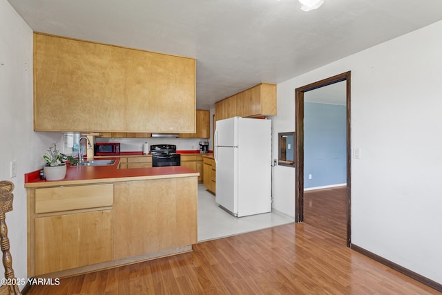808 S 72nd Ave, Yakima, WA 98908 - kitchen featuring freestanding refrigerator, black electric range oven, a peninsula, a sink, and light wood-style floors