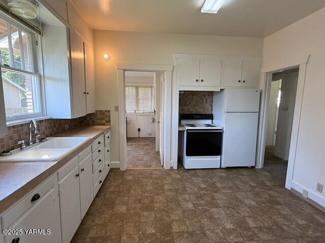 1216 S 44th Ave, Yakima, WA 98908 - kitchen with white appliances, a sink, decorative backsplash, and white cabinetry