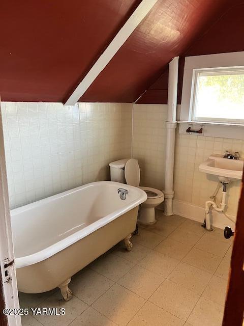 3 S Elm St, Toppenish, WA 98948 - bathroom featuring toilet, tile walls, a freestanding bath, a sink, and vaulted ceiling