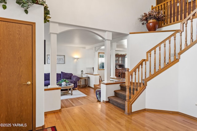 foyer featuring ornate columns, stairway, arched walkways, and wood finished floors