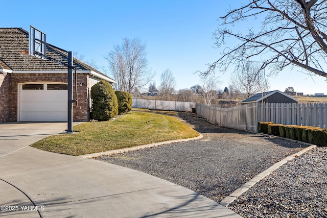 view of yard with a garage, concrete driveway, and fence