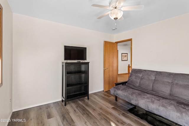 living area featuring ceiling fan, baseboards, and wood finished floors