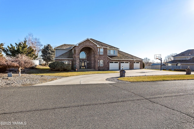 traditional-style house with a garage, concrete driveway, brick siding, and fence