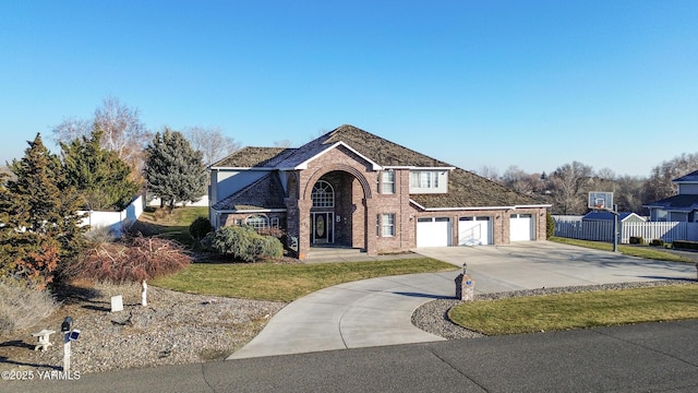 traditional-style house with an attached garage, brick siding, fence, driveway, and a front yard