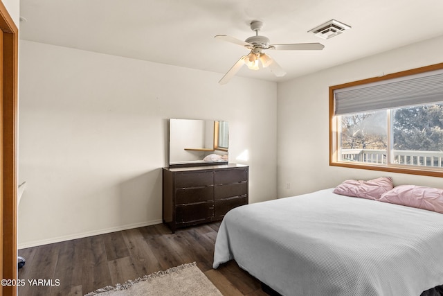 bedroom with dark wood-style floors, ceiling fan, visible vents, and baseboards