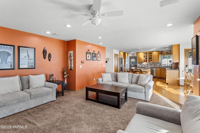 living room featuring a ceiling fan, recessed lighting, visible vents, and light colored carpet