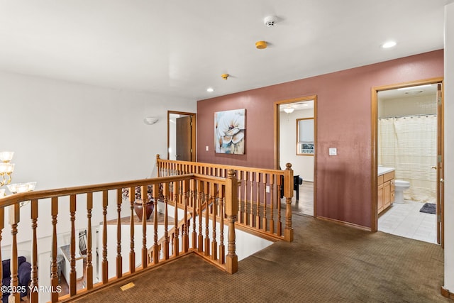 corridor featuring dark carpet, an upstairs landing, and recessed lighting