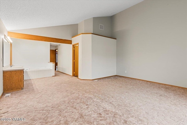 spare room featuring lofted ceiling, a textured ceiling, visible vents, and light colored carpet