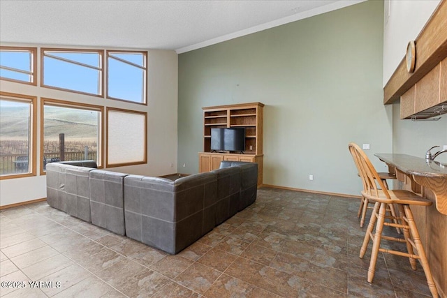 living room with a towering ceiling, crown molding, baseboards, and a textured ceiling