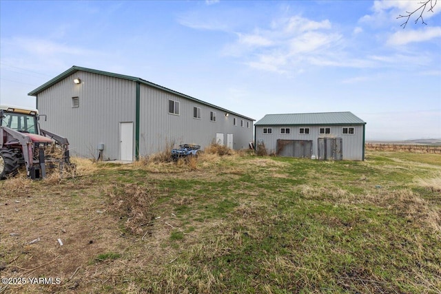 back of property with an outbuilding, a pole building, and a lawn