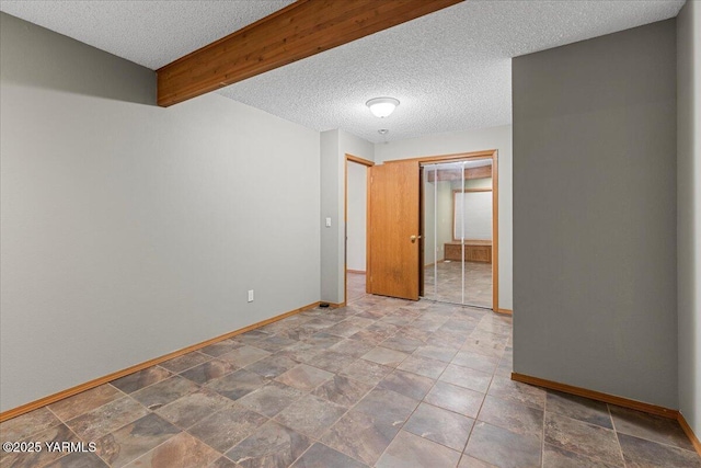 unfurnished bedroom with beam ceiling, a textured ceiling, baseboards, and a closet