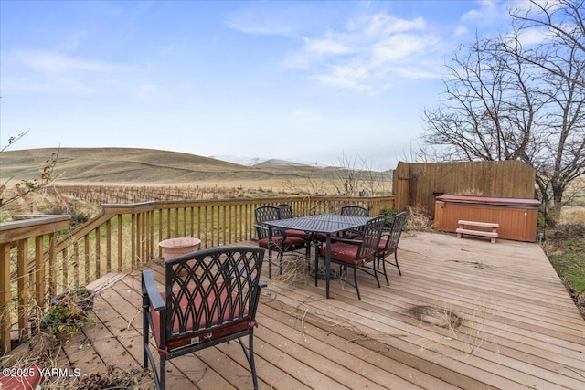 wooden deck with outdoor dining area, a mountain view, and a hot tub