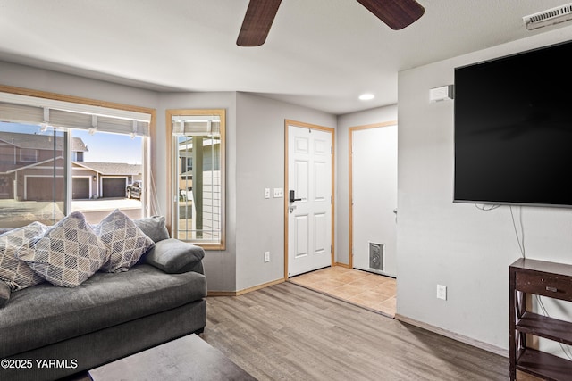 living area featuring baseboards, a ceiling fan, wood finished floors, and visible vents