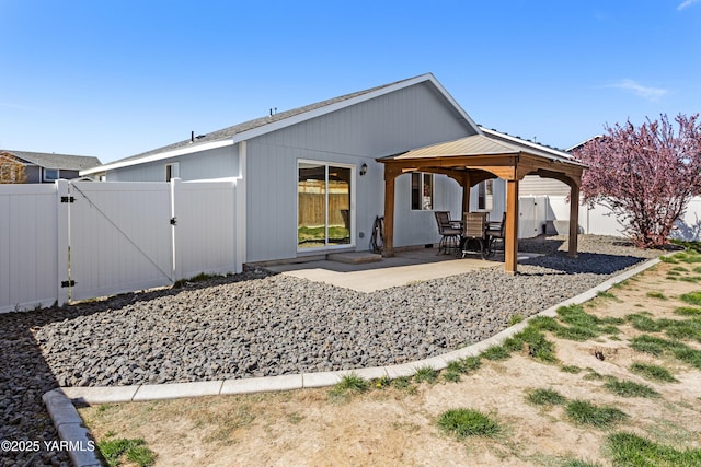 rear view of property featuring a patio, a fenced backyard, a gate, metal roof, and a gazebo