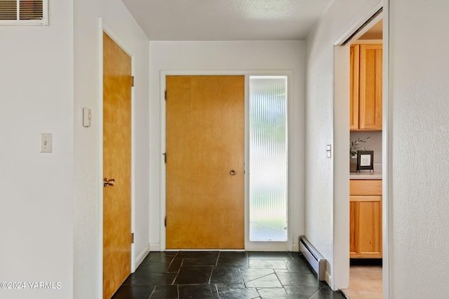 doorway to outside with visible vents, baseboard heating, and stone tile flooring