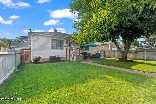 rear view of property with a yard and a fenced backyard