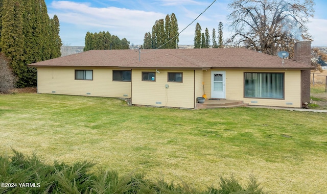 back of property with crawl space, roof with shingles, and a lawn