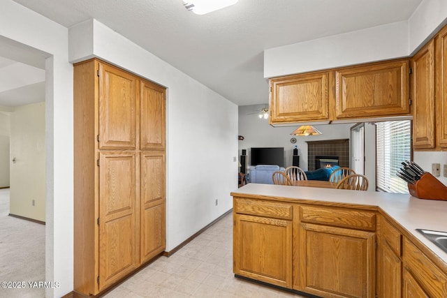 5304 Channel Dr, Yakima, WA 98901 - kitchen featuring a peninsula, a tile fireplace, and brown cabinets