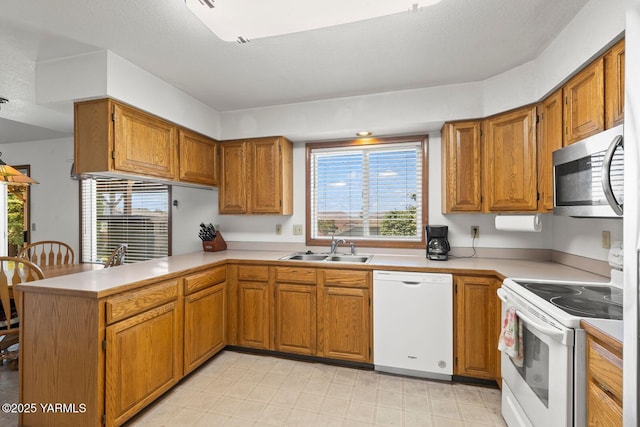 5304 Channel Dr, Yakima, WA 98901 - kitchen with white appliances, a peninsula, light countertops, and brown cabinetry