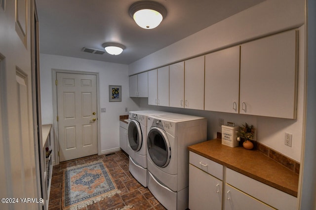 laundry area with visible vents, stone finish flooring, cabinet space, and washer and clothes dryer