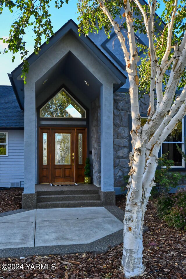 doorway to property featuring stone siding and a shingled roof