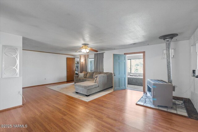 101 W Slavin Rd, Yakima, WA 98903 - living room with a wood stove, wood finished floors, a ceiling fan, and a textured ceiling