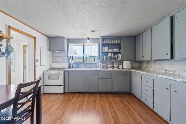 101 W Slavin Rd, Yakima, WA 98903 - kitchen featuring white gas stove, gray cabinetry, light wood-style floors, tasteful backsplash, and a textured ceiling
