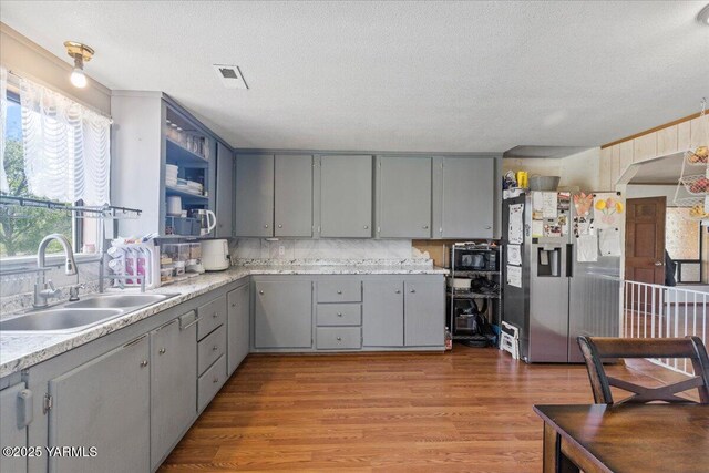 101 W Slavin Rd, Yakima, WA 98903 - kitchen with gray cabinetry, black microwave, stainless steel fridge with ice dispenser, light wood-type flooring, and a textured ceiling