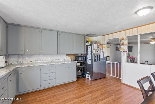 101 W Slavin Rd, Yakima, WA 98903 - kitchen with stainless steel refrigerator with ice dispenser, gray cabinets, a textured ceiling, black microwave, and light wood finished floors