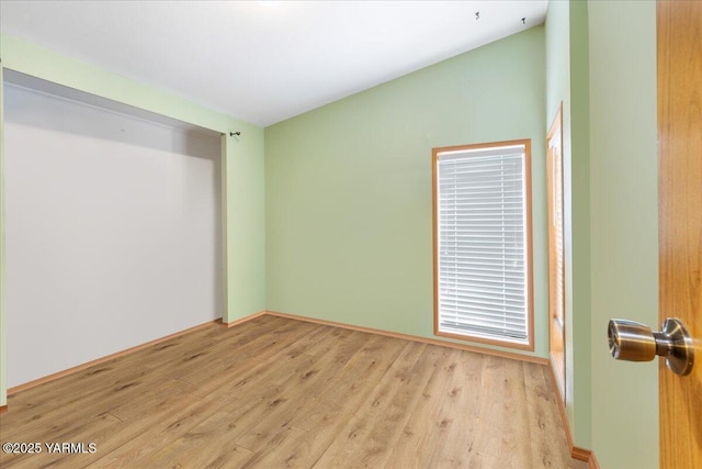 spare room with lofted ceiling and light wood-style flooring