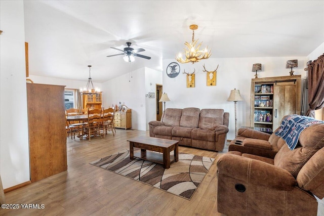 living room with light wood-style flooring and ceiling fan with notable chandelier