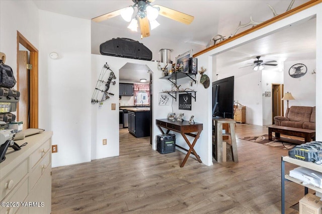 kitchen with arched walkways, light countertops, wood finished floors, and a ceiling fan