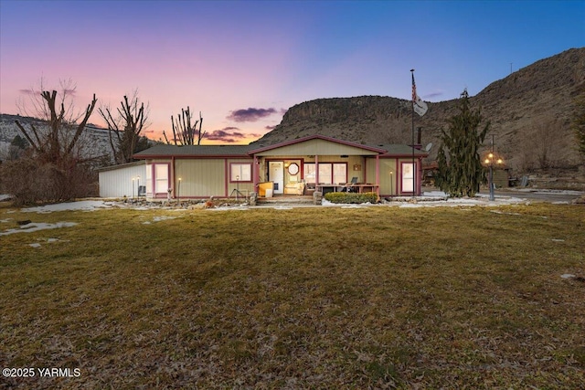 rear view of house with covered porch, a yard, and a mountain view