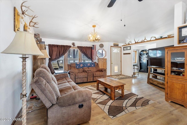 living area with ceiling fan with notable chandelier and light wood finished floors