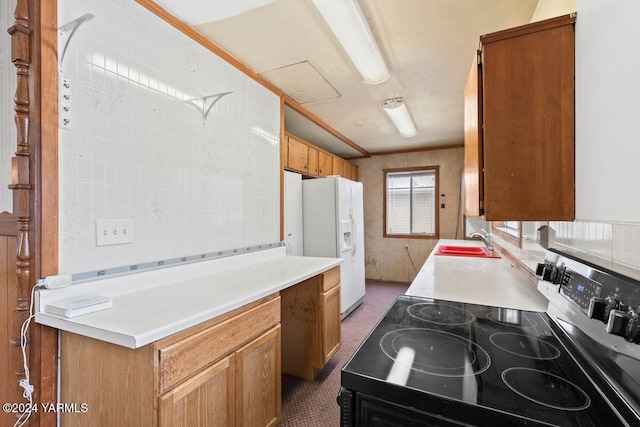 kitchen with light countertops, brown cabinetry, stainless steel electric range, and a sink