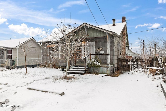 view of front of house featuring a chimney and fence