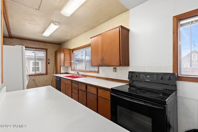 kitchen featuring brown cabinets, black appliances, light countertops, and a sink