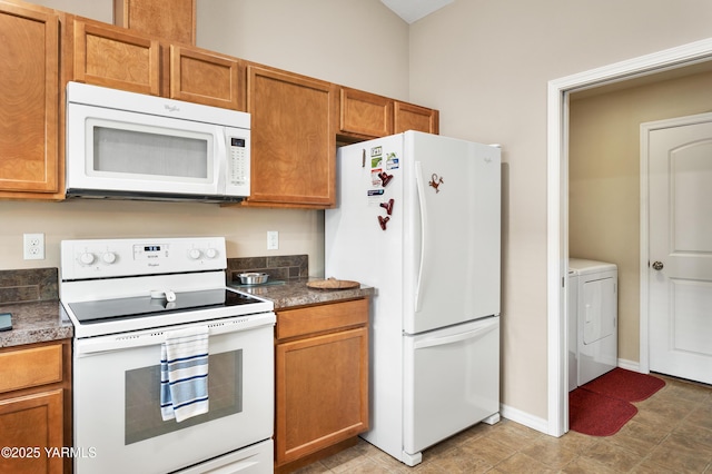 kitchen featuring baseboards, white appliances, brown cabinets, and washing machine and dryer