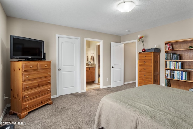 carpeted bedroom with ensuite bath, a textured ceiling, and baseboards