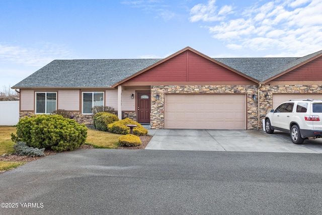 view of front facade with fence, driveway, roof with shingles, stone siding, and a garage