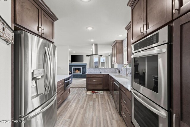 419 N 62nd Ave, Yakima, WA 98908 - kitchen with light wood finished floors, stainless steel appliances, light countertops, a sink, and open floor plan