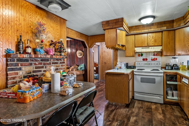 1523 Roosevelt Ave, Yakima, WA 98902 - kitchen with electric range, under cabinet range hood, brown cabinets, wooden walls, and dark wood finished floors