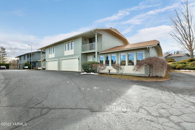 view of front of property featuring a garage, aphalt driveway, and a balcony