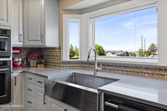 kitchen featuring backsplash, a sink, dishwashing machine, black oven, and oven