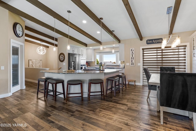 kitchen with a breakfast bar area, stainless steel appliances, baseboards, and white cabinetry