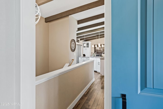hall with dark wood-style flooring, an upstairs landing, and beamed ceiling