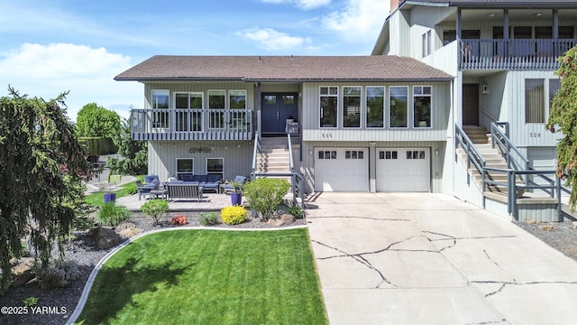 view of front of house with a shingled roof, an attached garage, stairway, a balcony, and driveway