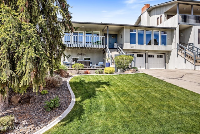 view of front of home featuring driveway, a chimney, a front yard, stairway, and an attached garage