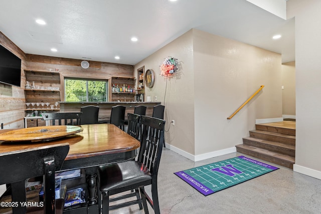 dining room featuring recessed lighting, baseboards, stairway, and indoor bar
